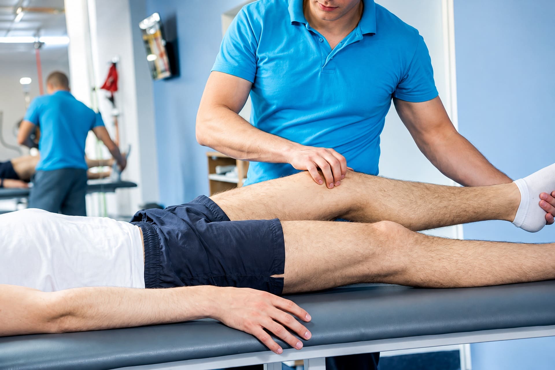 Fysiotherapeut onderzoekt de knie van een patiënt op de behandeltafel