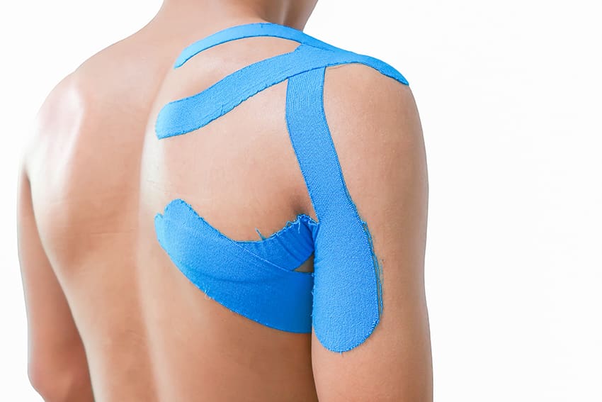 Blauwe medical tape aangebracht op een schouder en bovenarm