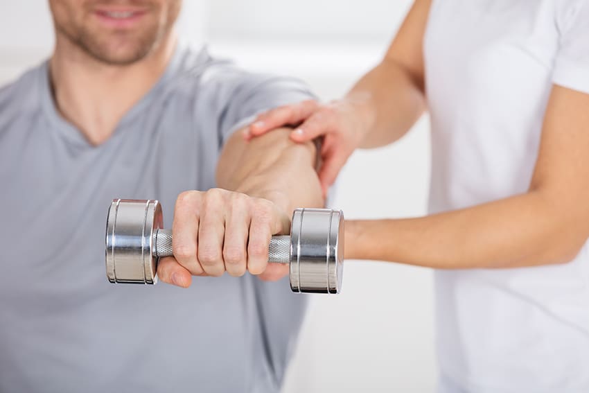 Therapeut ondersteunt de arm van een man die een halter optilt