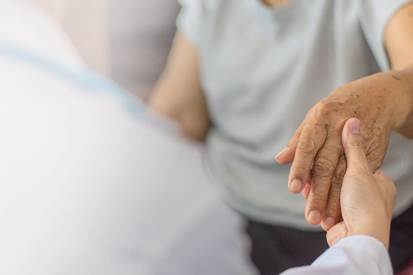 Therapeut houdt de hand van een oudere patiënt vast tijdens een gesprek